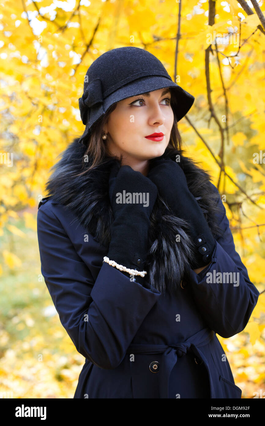 La donna in un cappello nero su sfondo di autumn tree Foto Stock