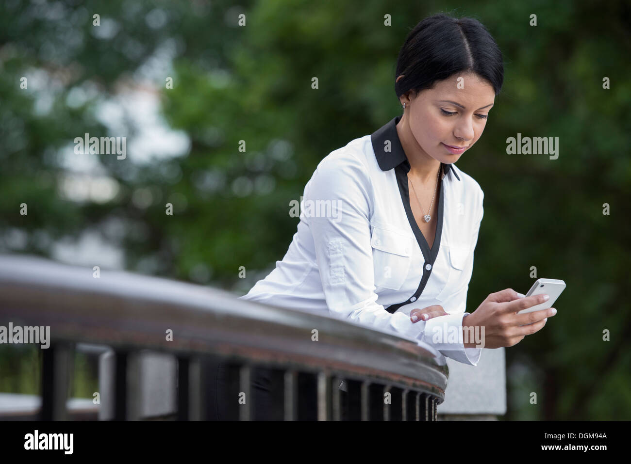 La gente di affari. Una donna in una camicia bianca controllando il suo telefono. Foto Stock