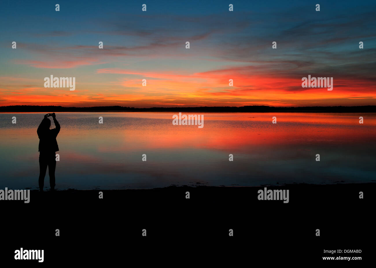 Una donna fotografa il tramonto su Lac d'orientare a Mesnil Sant Pere, Francia sul suo smartphone. Foto Stock