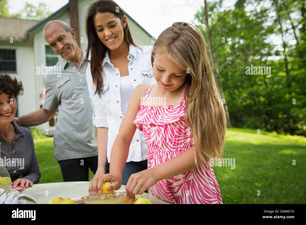 Un estate incontro di famiglia in una fattoria. Una ragazza per affettare e spremere il succo dei limoni per rendere una limonata. Foto Stock