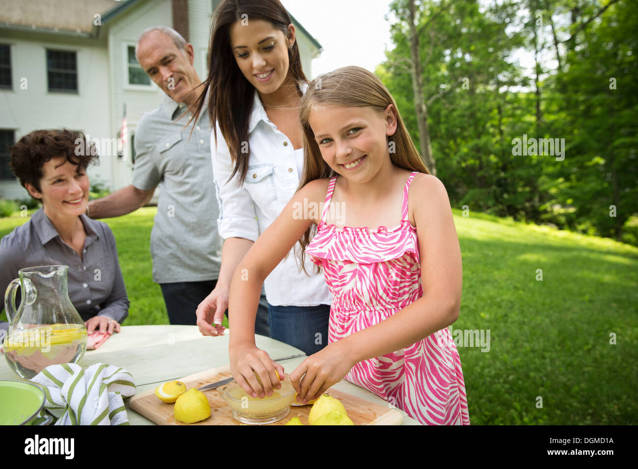 Un estate incontro di famiglia in una fattoria. Una ragazza per affettare e spremere il succo dei limoni per rendere una limonata. Foto Stock