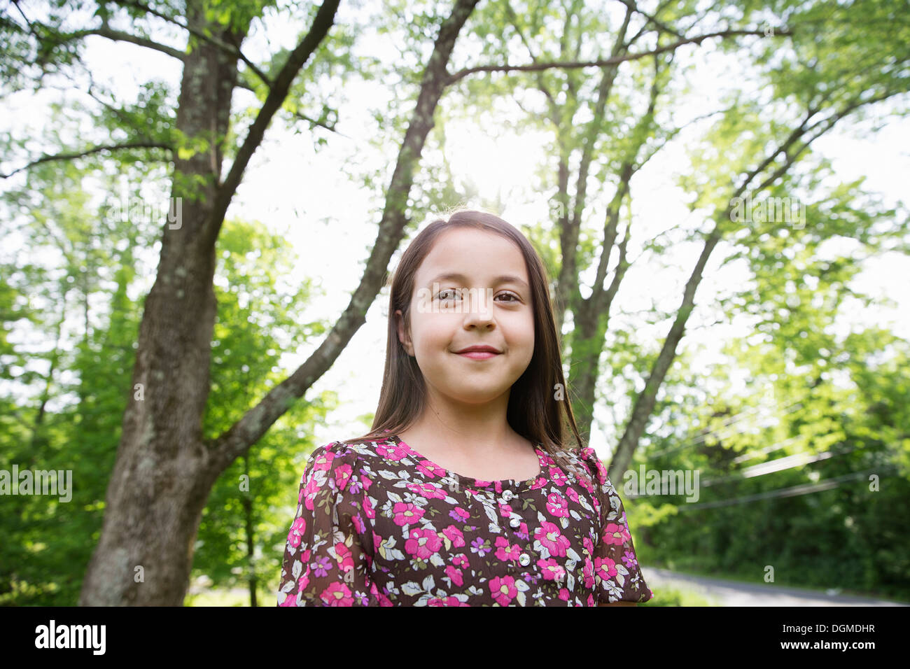 Una giovane ragazza in un modellato abiti estivi, sotto l'ombra degli alberi in un casale giardino. Foto Stock