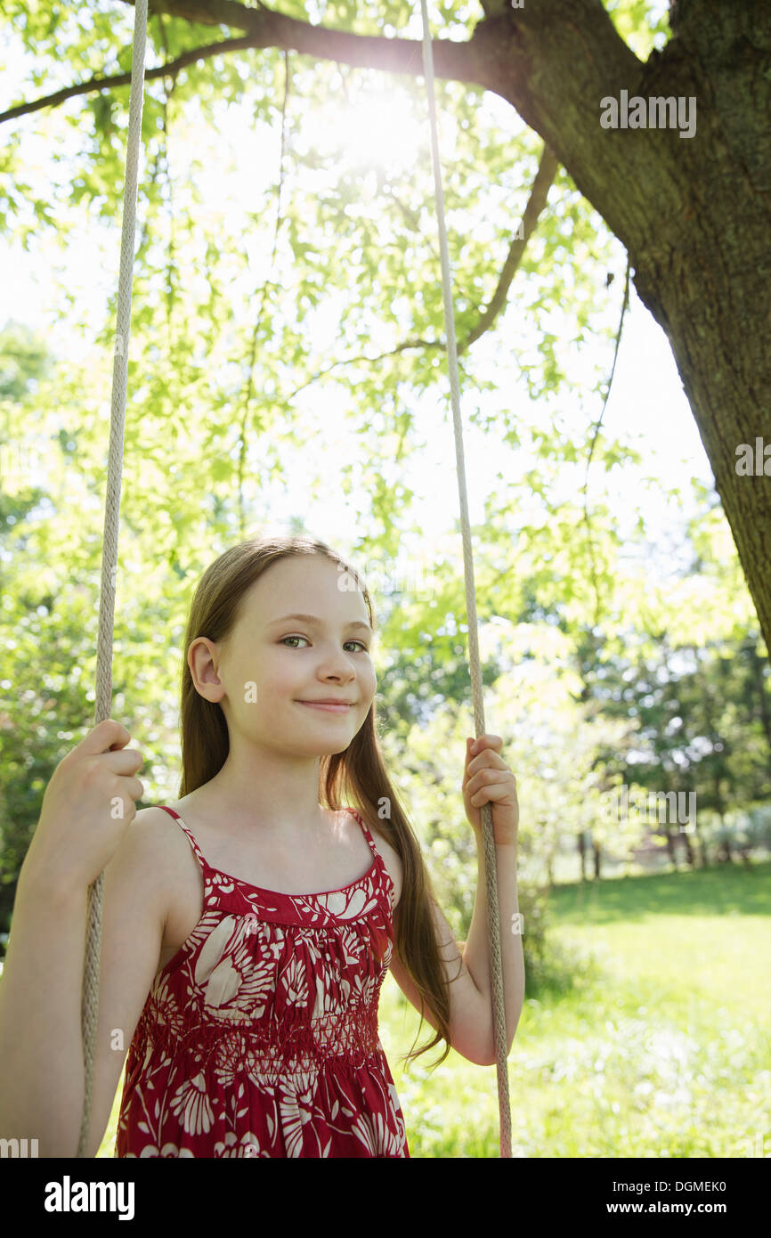 L'estate. Una ragazza in un sundress su uno swing in un frutteto. Foto Stock