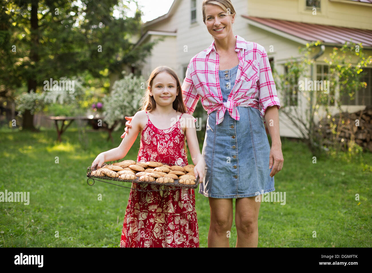 La cottura biscotti fatti in casa. Una giovane ragazza con un vassoio di biscotti appena sfornati e una donna adulta accanto a lei. Foto Stock