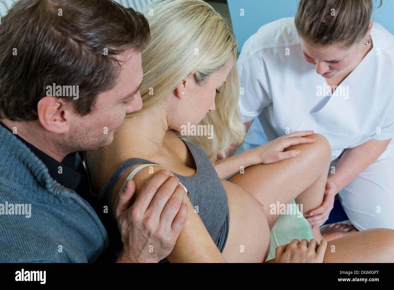 L uomo e la donna nella sala parto durante il parto, la donna è seduta su uno sgabello di nascita durante il travaglio e viene supportato Foto Stock