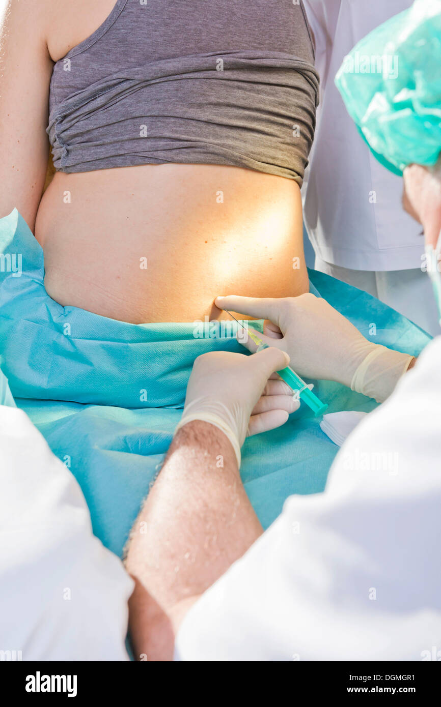 Donne in stato di gravidanza durante la consegna in camera di mandata con un anestesista applicando un PDA o epidurale, Germania Foto Stock