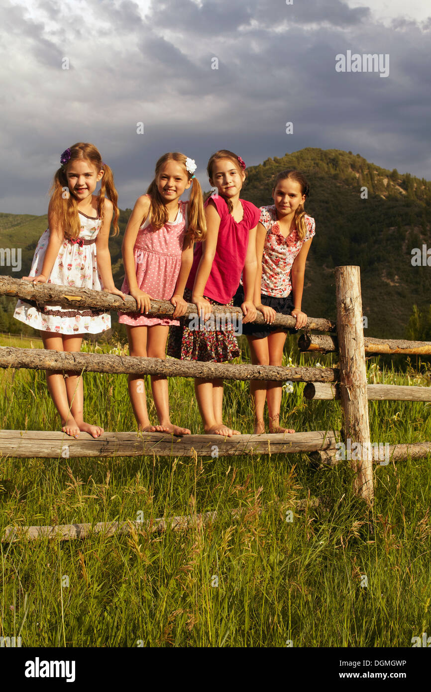 Stati Uniti d'America, Colorado, quattro amiche (6-7, 8-9, 10-11) permanente sulla recinzione in legno in erba Foto Stock