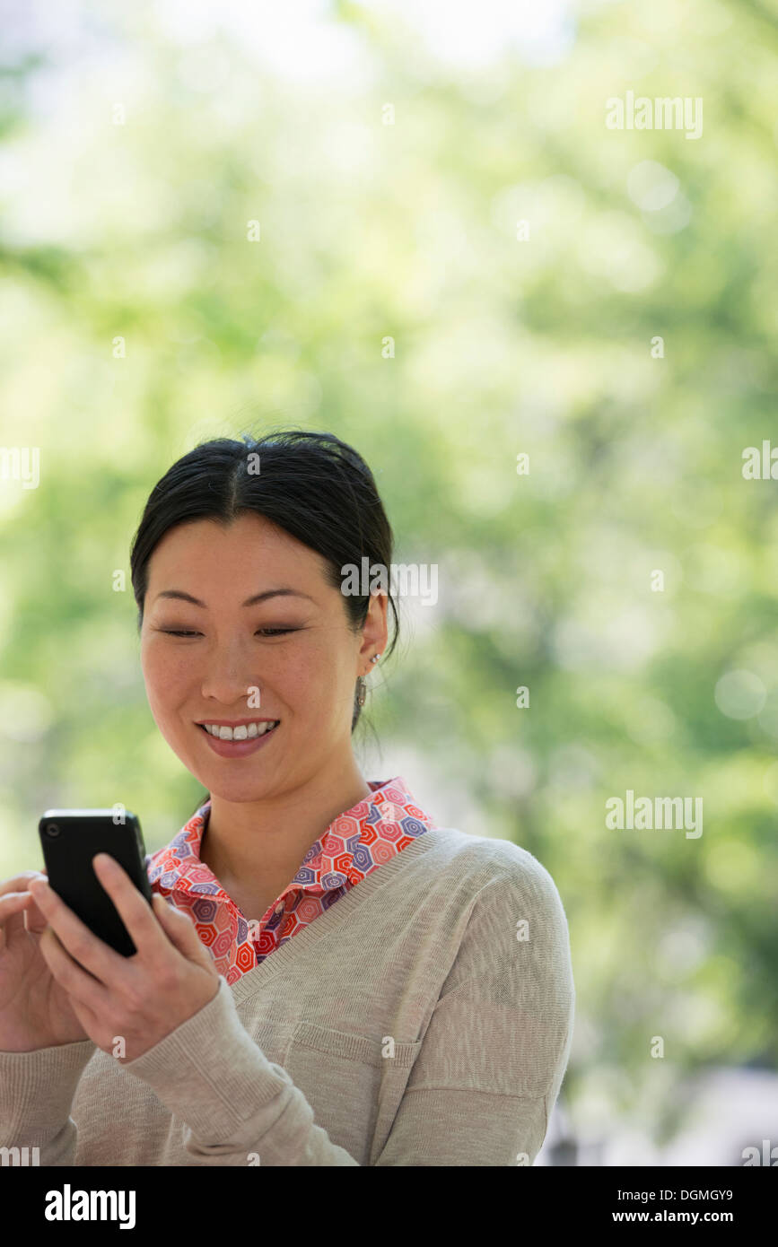 L'estate. La gente di affari. Una donna controllando il suo smart phone per i messaggi. Foto Stock