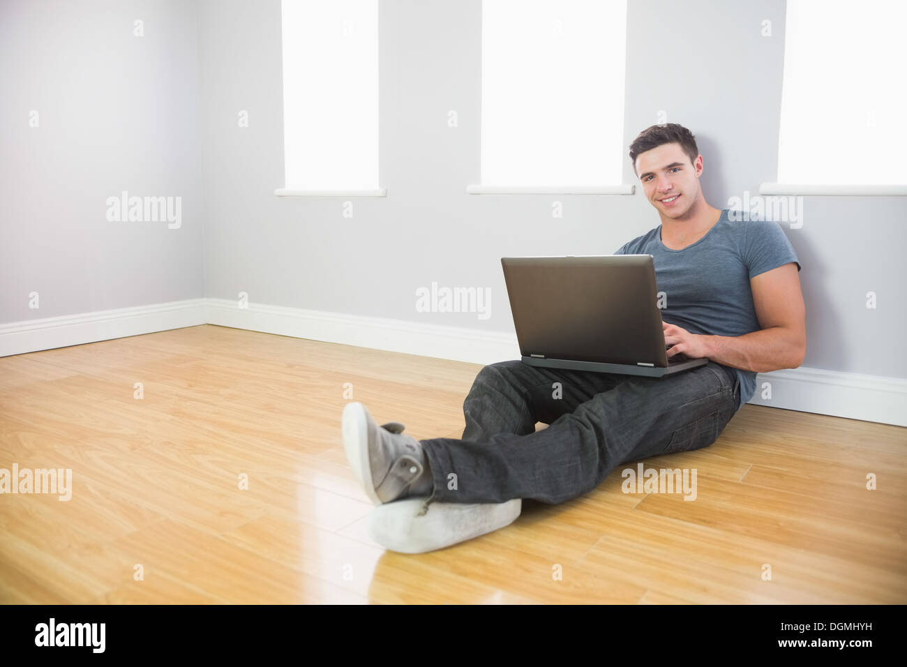 Allegro uomo bello appoggiata contro la parete utilizzando laptop Foto Stock