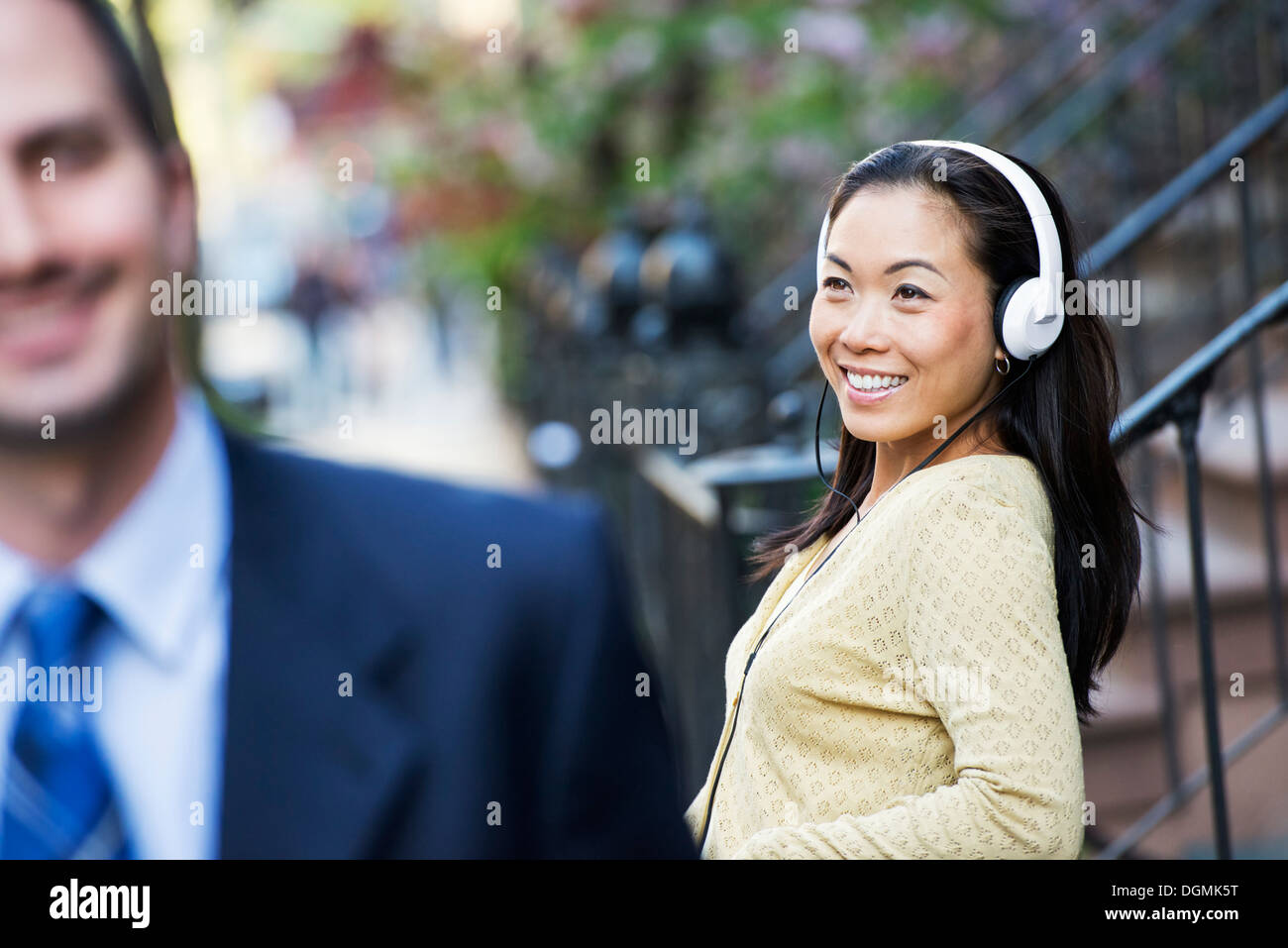 Una donna che indossa le cuffie musicali e un uomo in un business suit. Foto Stock