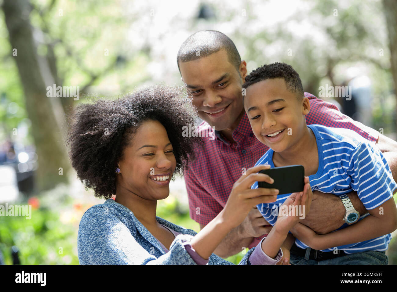 Una famiglia nel parco in una giornata di sole. Scattare fotografie con un telefono intelligente. Foto Stock