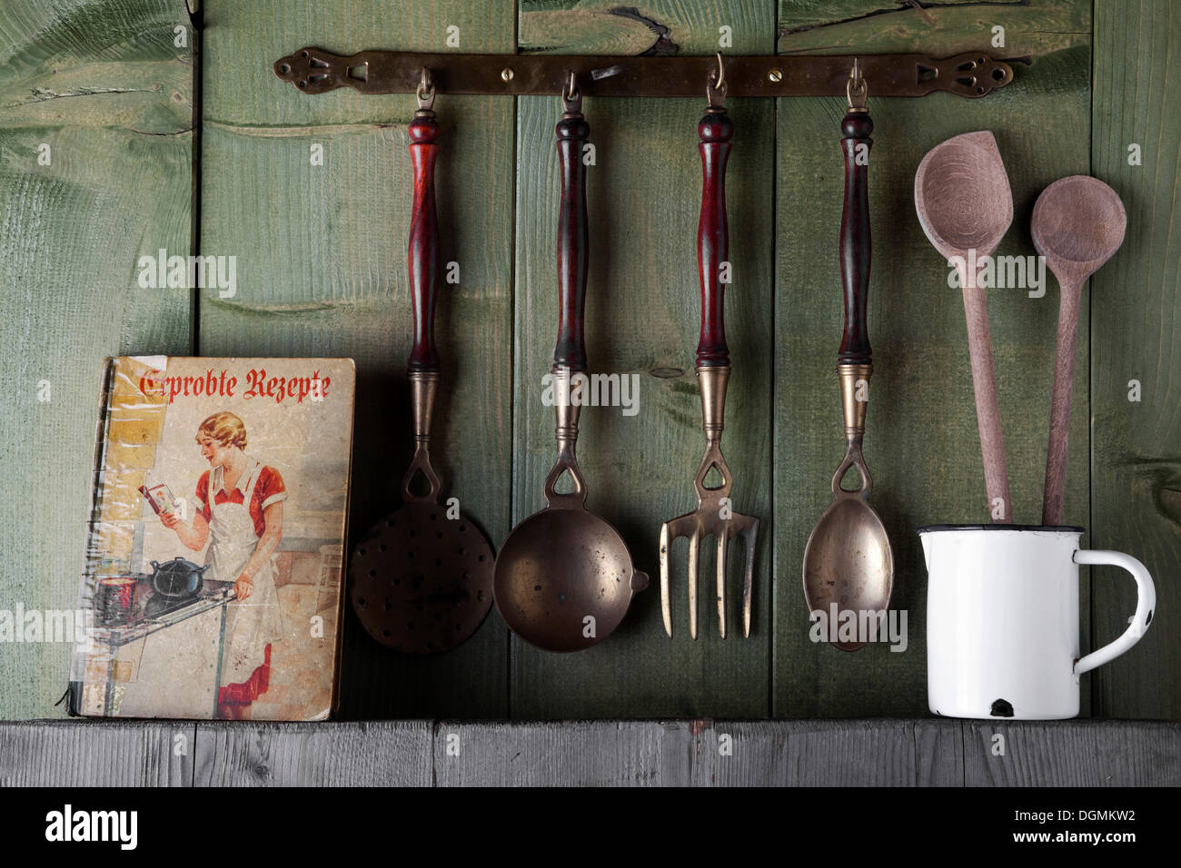 Il vecchio libro di cucina e utensili di cottura nella parte anteriore di un verde parete in legno, Germania Foto Stock