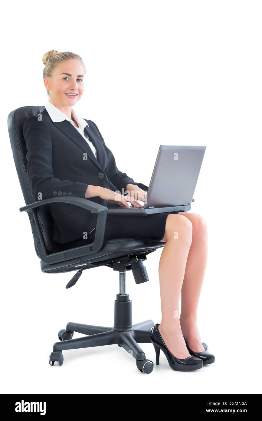Sorridente giovane imprenditrice seduto su una sedia da ufficio Foto Stock