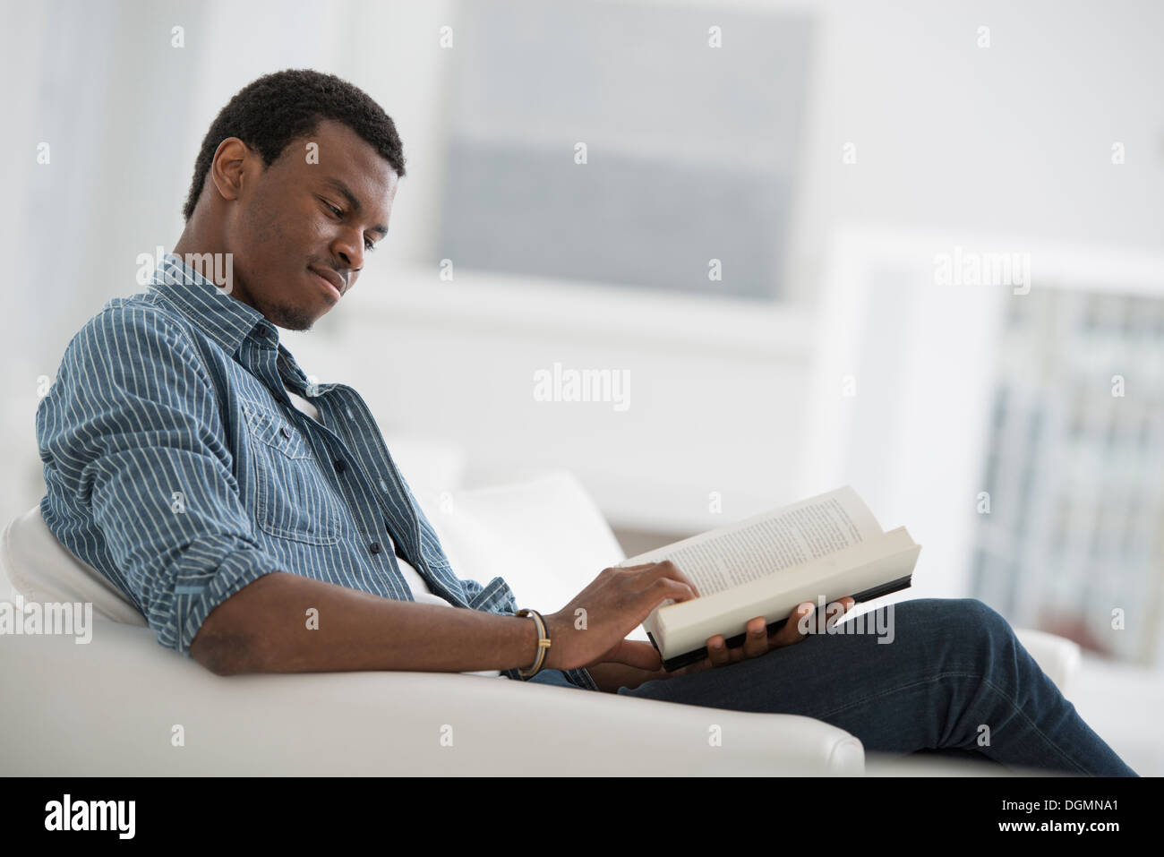 Un bianco luminoso con sala interna. Un uomo seduto a leggere un libro. Foto Stock