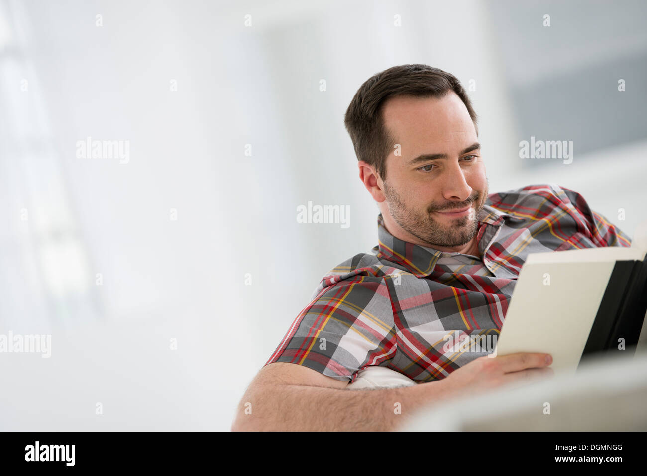 Un bianco luminoso con sala interna. Un uomo seduto a leggere un libro. Foto Stock