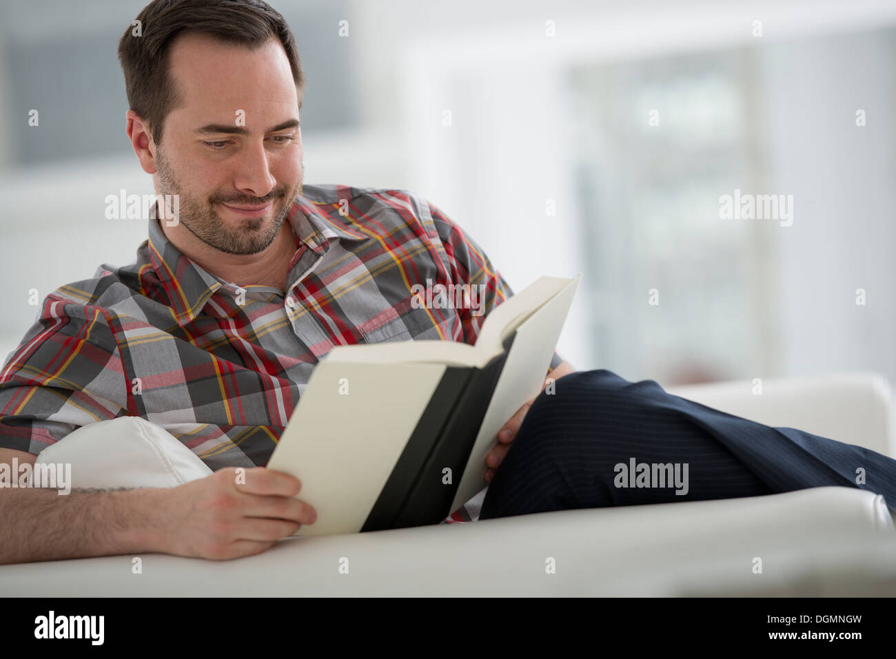 Un bianco luminoso con sala interna. Un uomo seduto a leggere un libro. Foto Stock