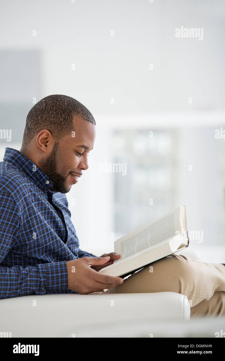 Un bianco luminoso con sala interna. Un uomo seduto a leggere un libro. Foto Stock