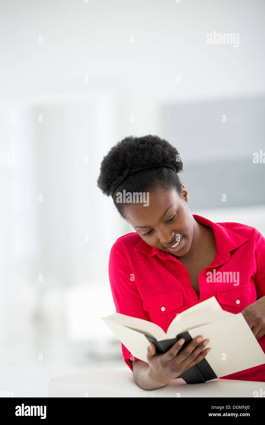 Un bianco luminoso con sala interna. Una donna seduta a leggere un libro. Foto Stock