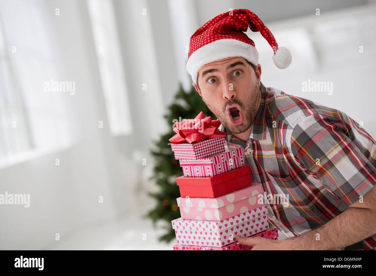 Ufficio interno. Per celebrare il Natale. Un uomo in un cappello da Babbo Natale una catasta di regali. Albero di Natale decorato. Foto Stock