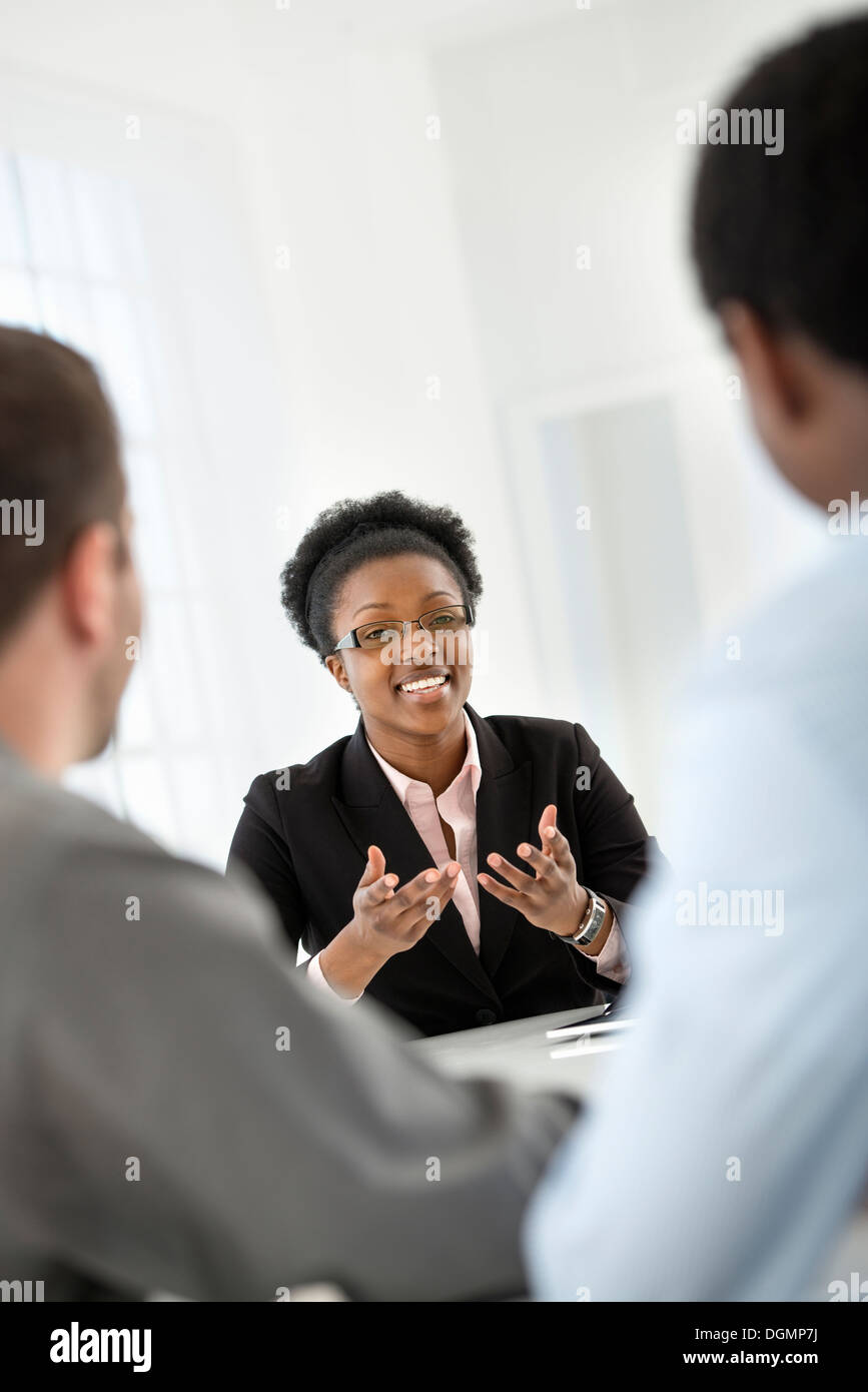 Ufficio interno. Tre persone sedute intorno ad un tavolo a un incontro di affari. Foto Stock