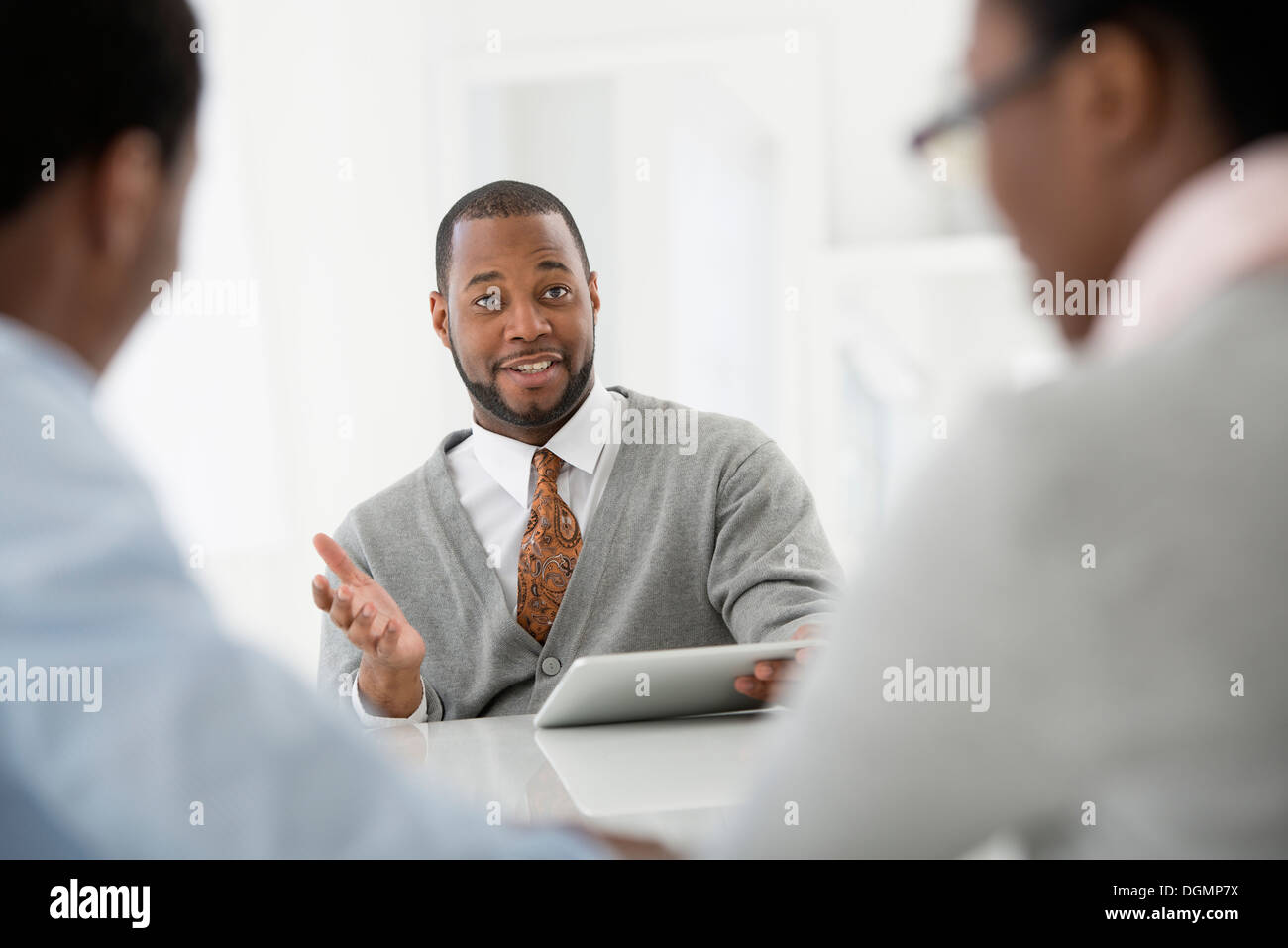 Ufficio interno. Tre persone sedute intorno ad un tavolo a un incontro di affari. Foto Stock