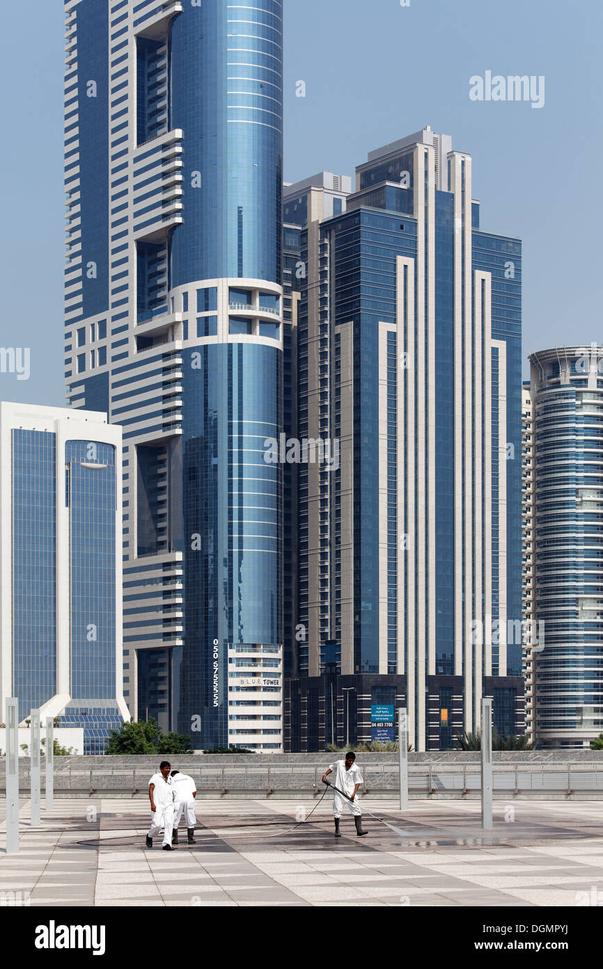 Pulizia dei lavoratori di un terrazzo davanti di grattacieli con un lavaggio ad alta pressione, Sheikh Zayed Road, Dubai, Emirati Arabi Uniti Foto Stock
