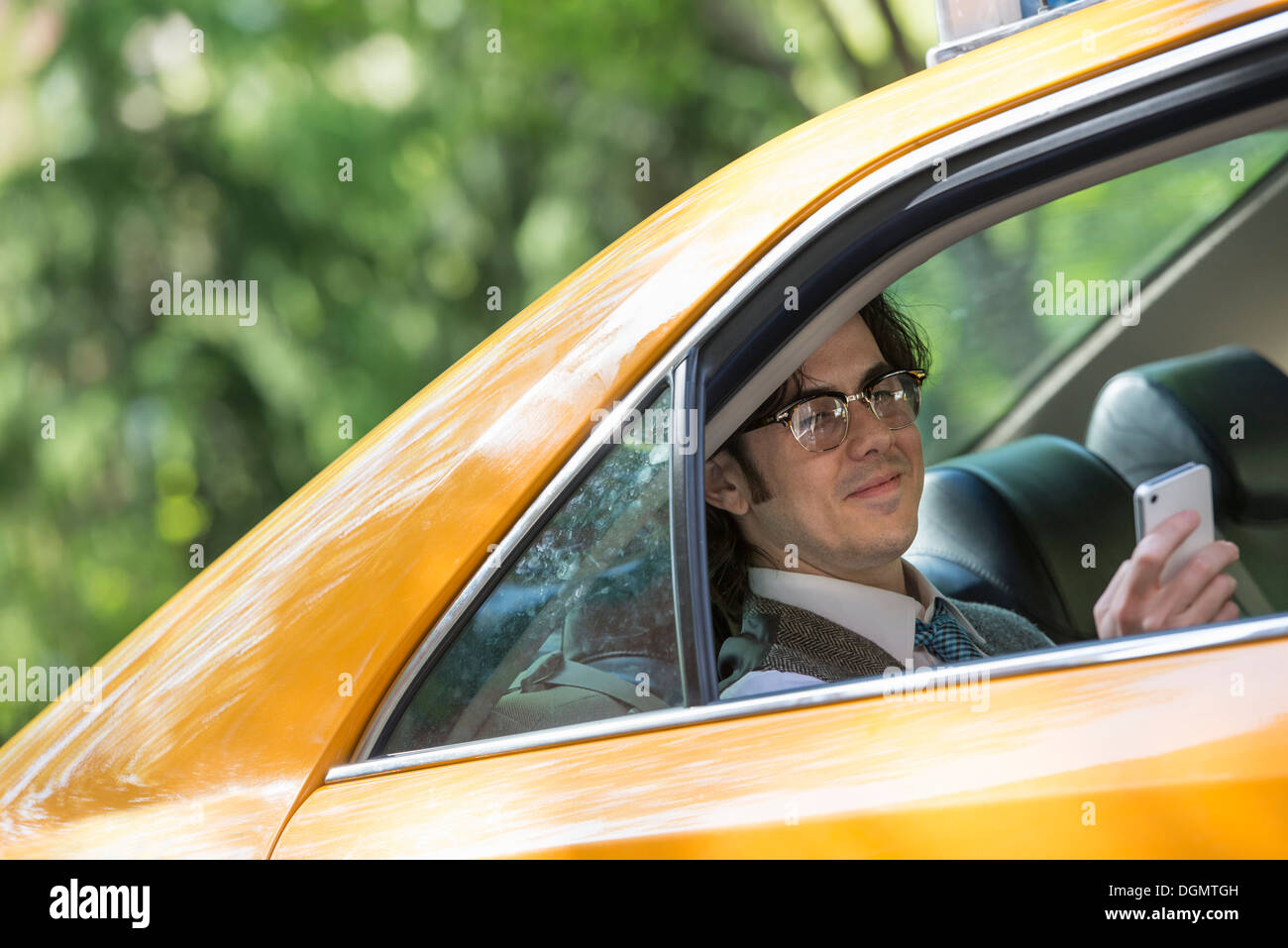 La vita della città. Le persone in movimento. Un giovane uomo nel sedile posteriore di un taxi. Foto Stock