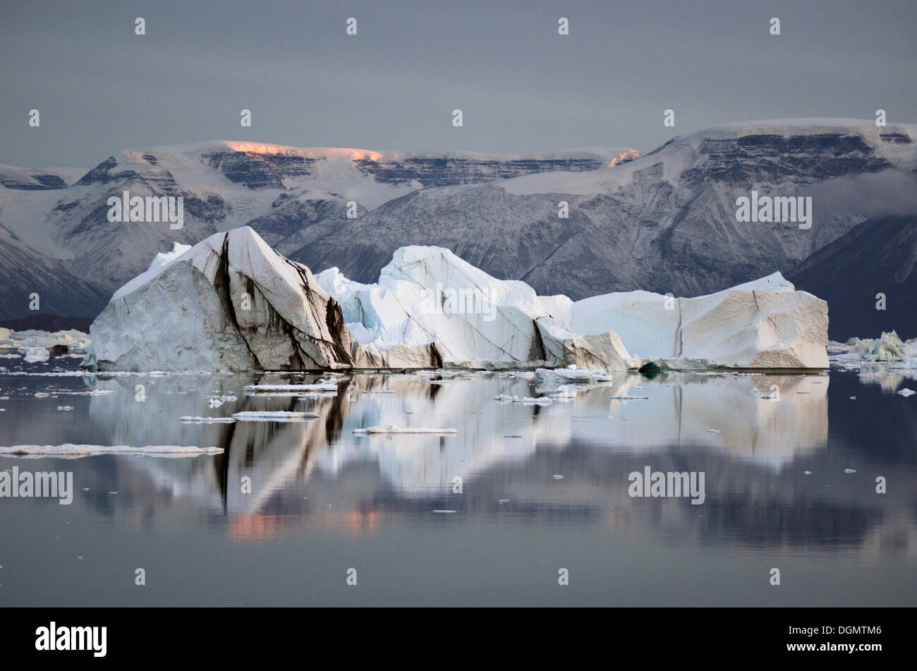 Iceberg e montagne nella luce della sera con riflessioni, Rødefjord, Scoresbysund, Sermersooq, Groenlandia Foto Stock