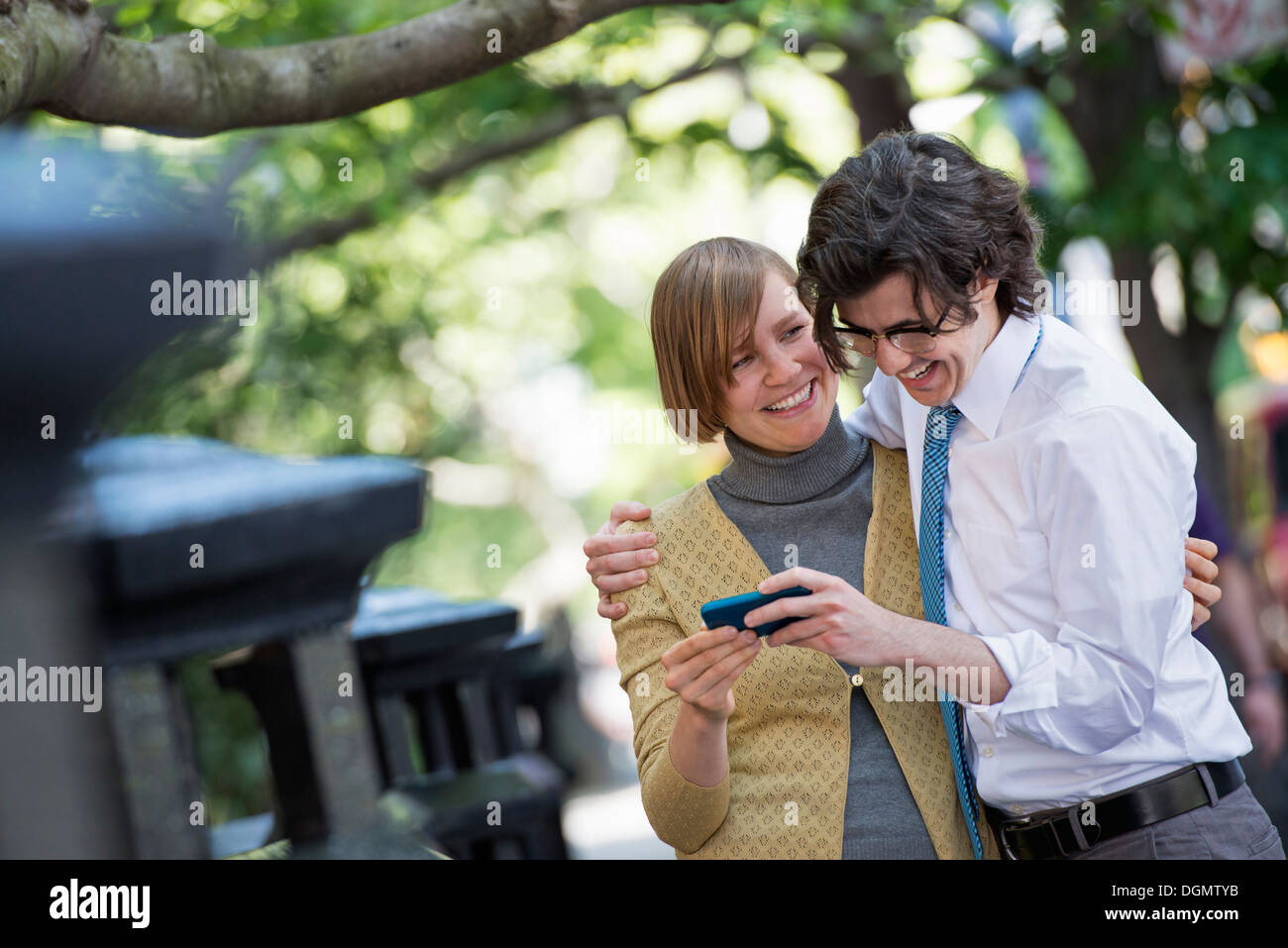 Città. Due persone, un uomo e una donna all'aperto, guardando uno smart phone insieme. Foto Stock