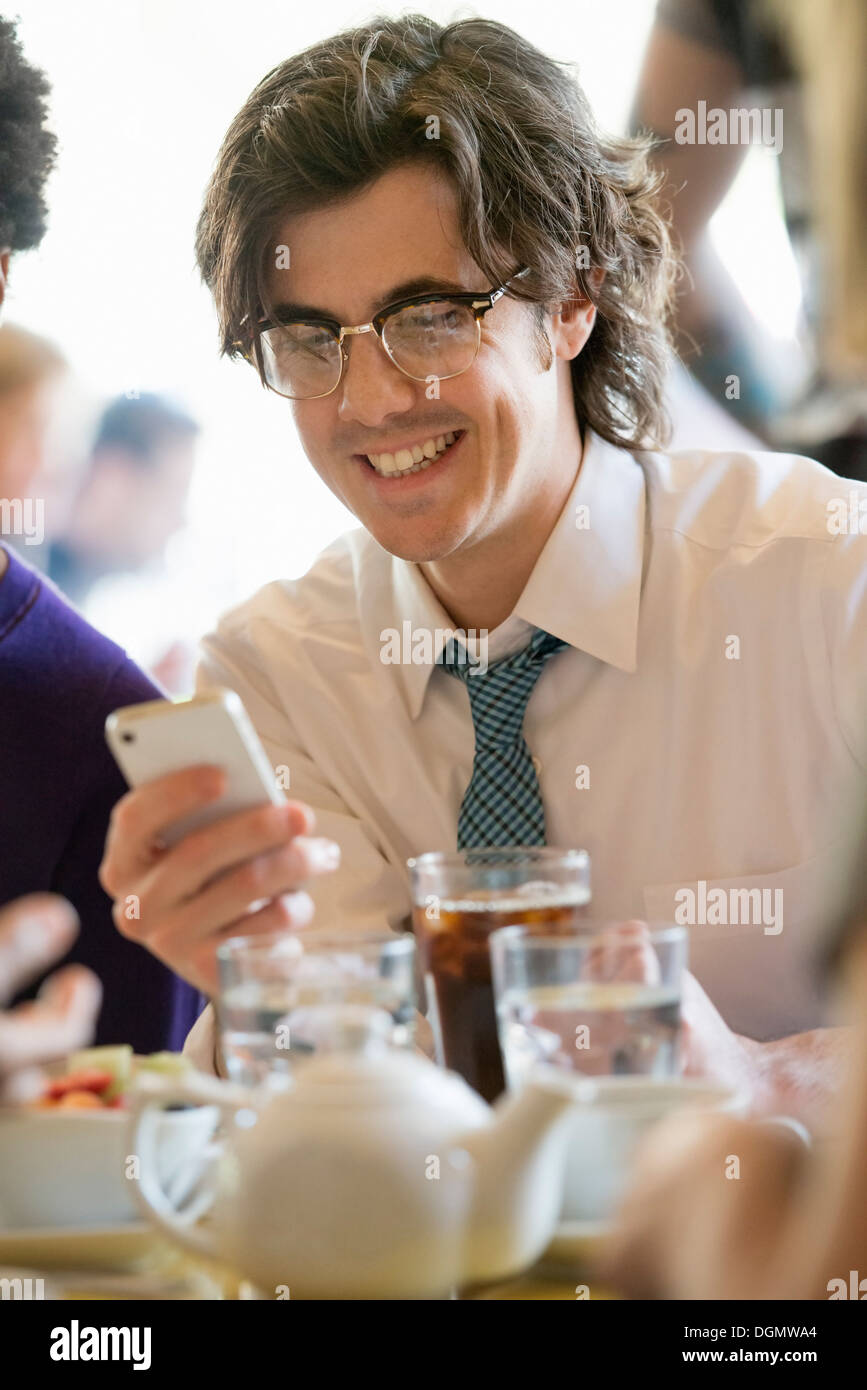 La vita della città. Un gruppo di persone in un café, controllando la loro smart phone. Foto Stock