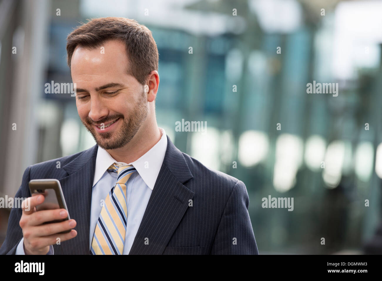 Città. Un uomo in un business suit controllare i suoi messaggi sul suo smart phone. Foto Stock