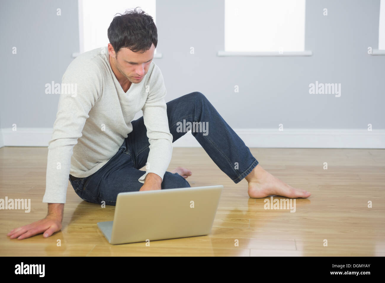 Casual buona Cerchi uomo seduto sul pavimento con il computer portatile Foto Stock