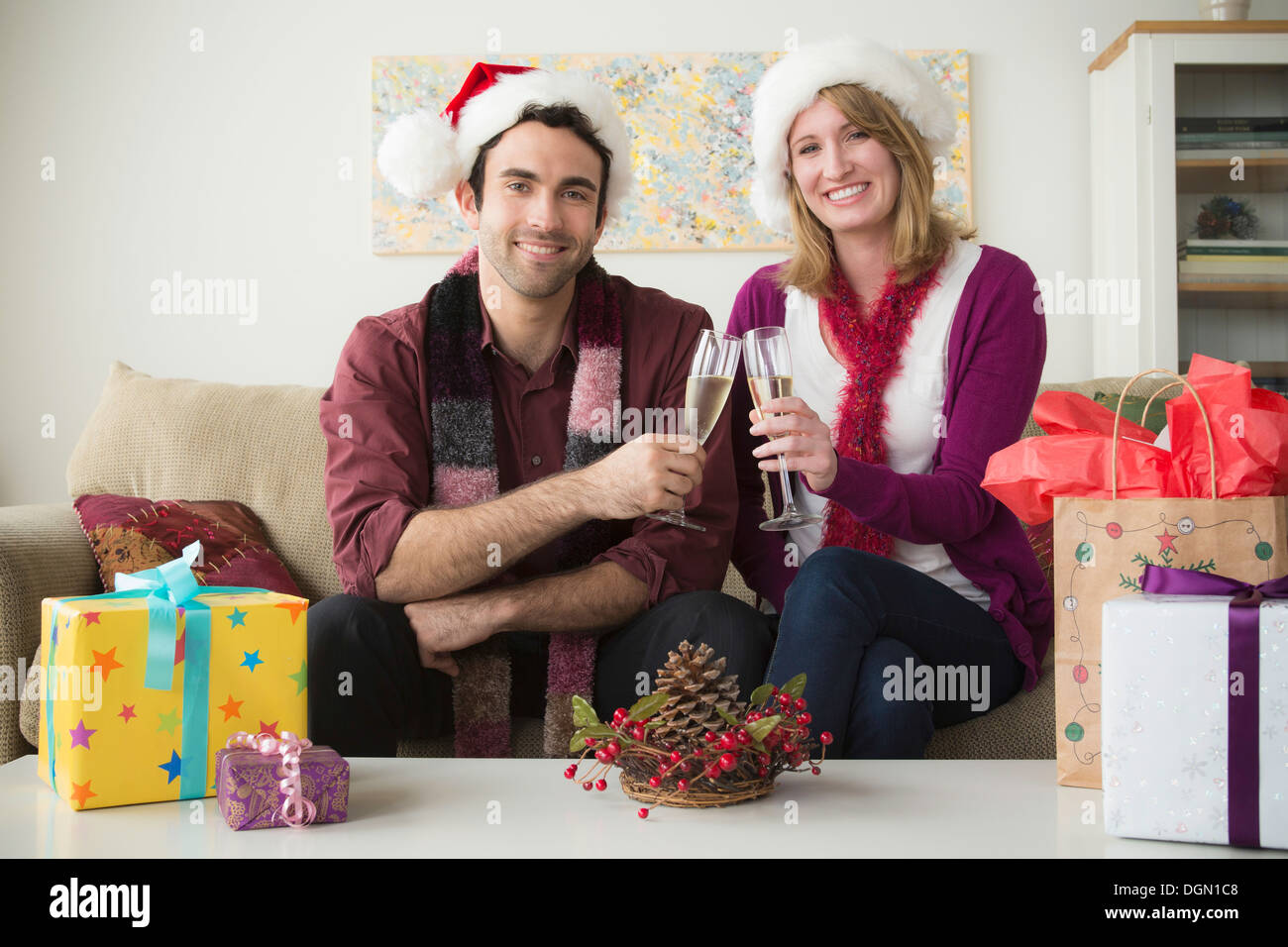 Ritratto di coppia giovane indossando cappelli di Babbo Natale bevendo champagne Foto Stock