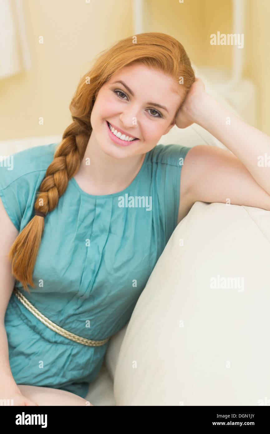Sorridente redhead seduta sul divano guardando la fotocamera Foto Stock