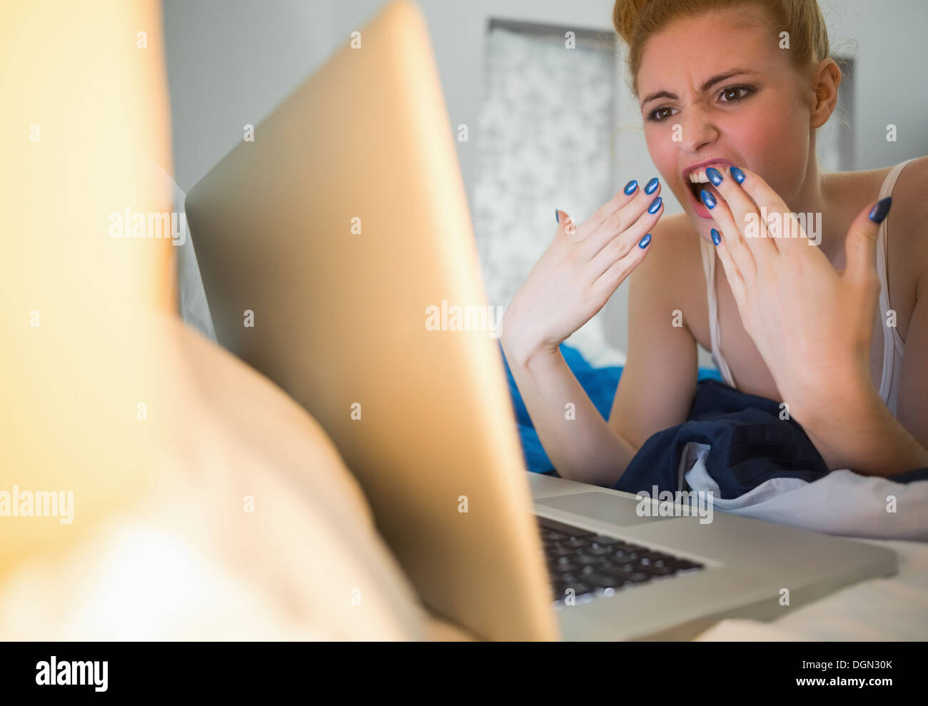 Scioccato redhead giacente sul suo letto tramite computer portatile Foto Stock