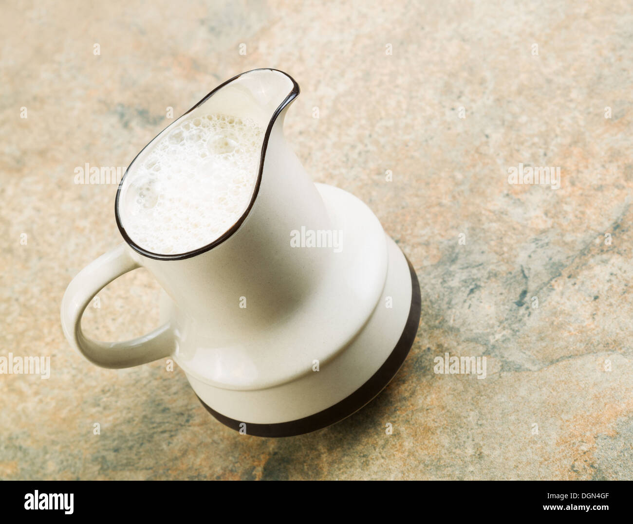 Foto angolata della brocca riempita con latte di mandorla seduta sul banco pietra top Foto Stock