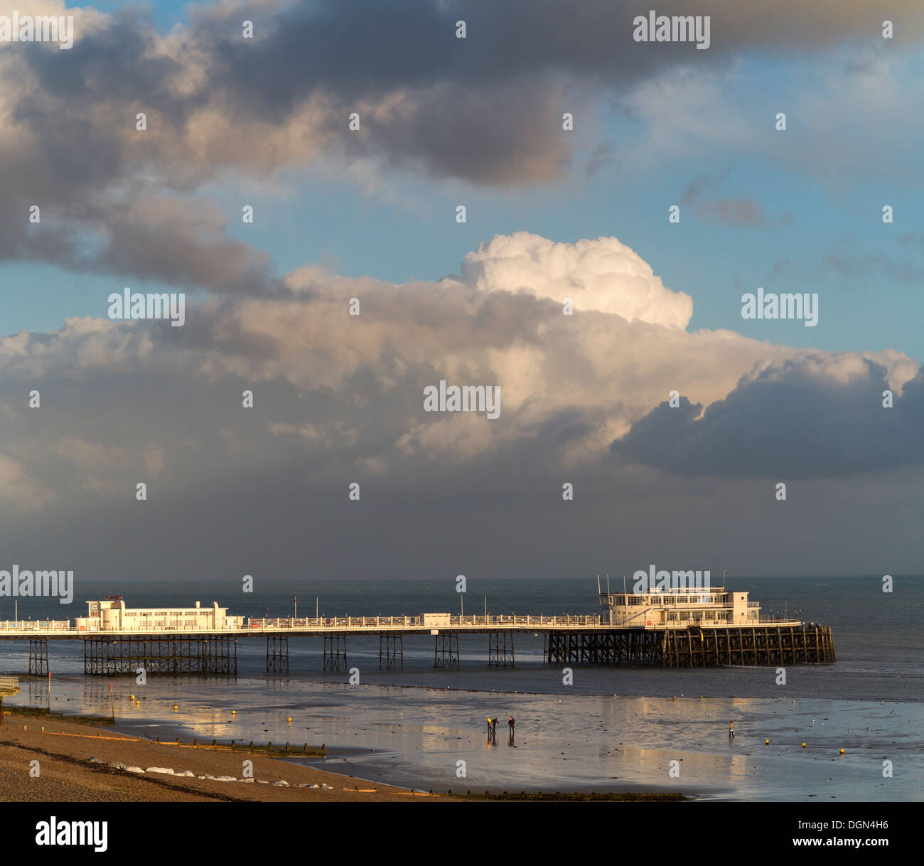 Luce della Sera sul lato ovest di Worthing pier si riflette in un mare di vongole con forte nuvole all'orizzonte Inghilterra Foto Stock