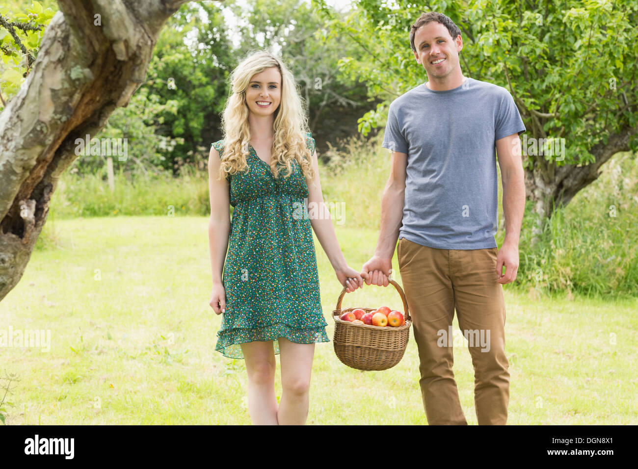 Coppia sorridente che porta un cesto di mele Foto Stock