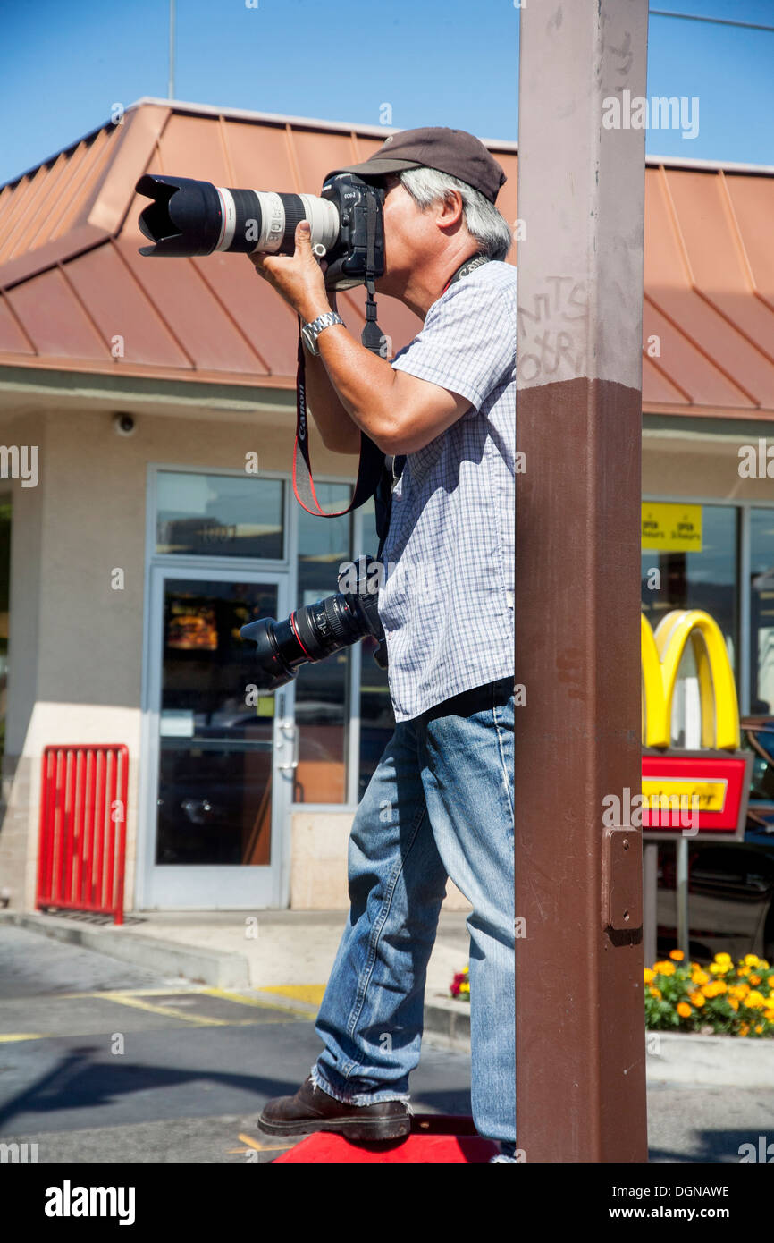 Portante due fotocamere digitali, Associated Press fotografo Nick Ut copre una dimostrazione del lavoro in una Los Angeles parcheggio. Foto Stock