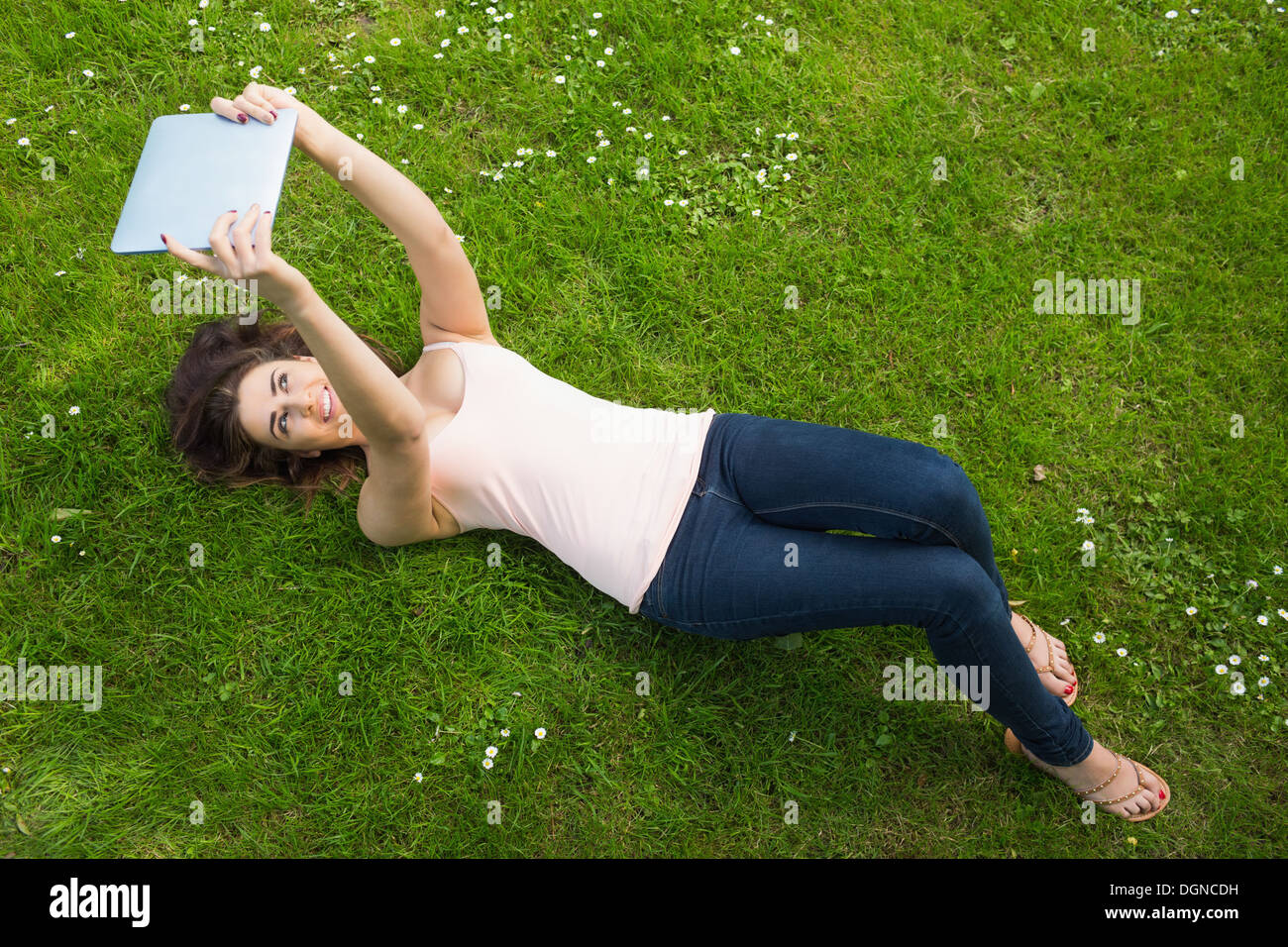 Felice giovane donna sdraiata su un prato utilizzando il suo tablet Foto Stock