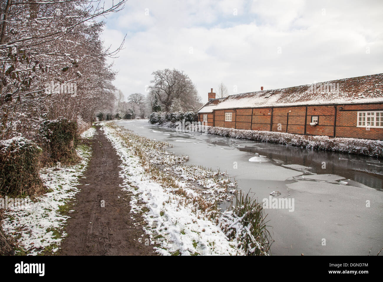 Terreni fangosi alzaia con neve sulla banca del fiume congelato Wey su un freddo e tetro inverno del giorno Foto Stock