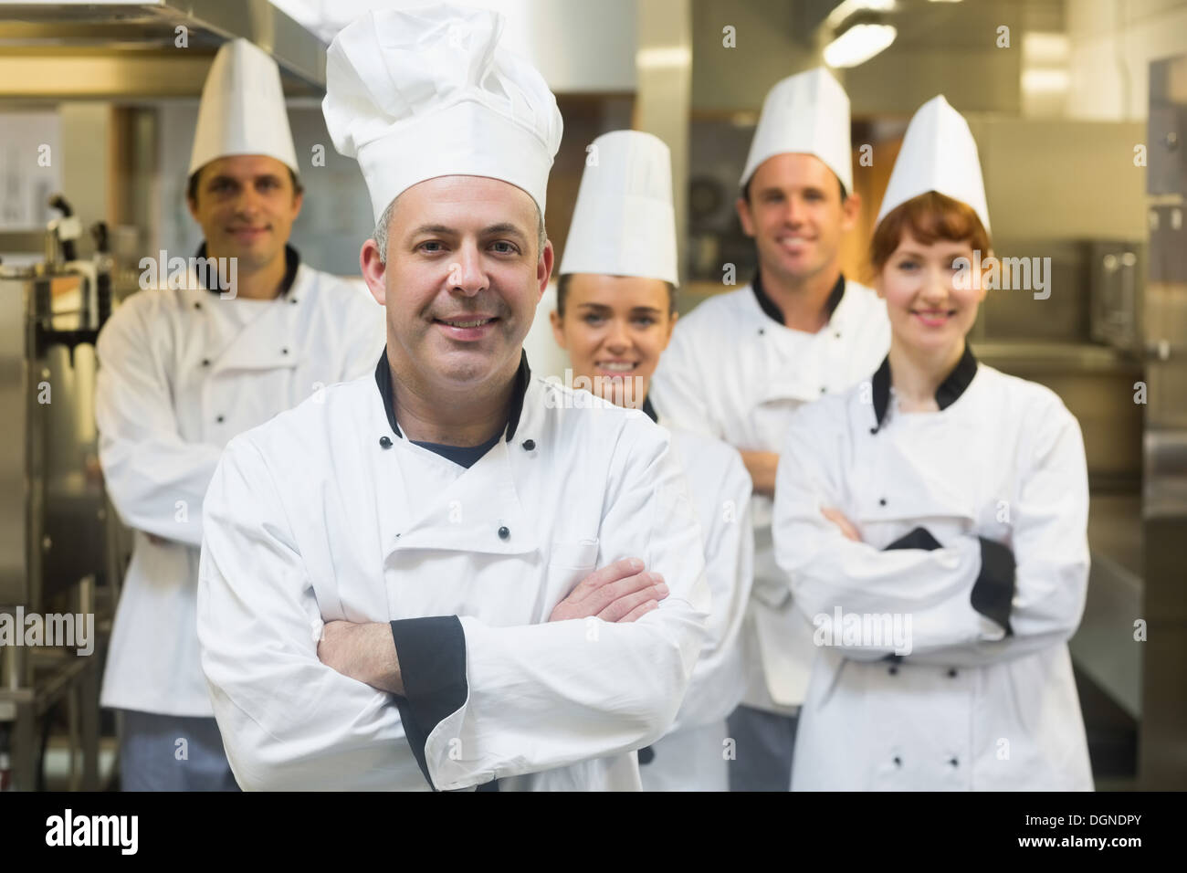 Cinque cuochi indossano uniformi in posa di una cucina Foto Stock