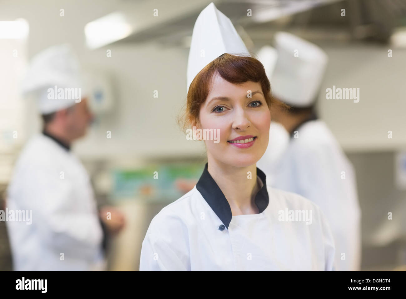 Donna sorridente chef in posa di una cucina Foto Stock