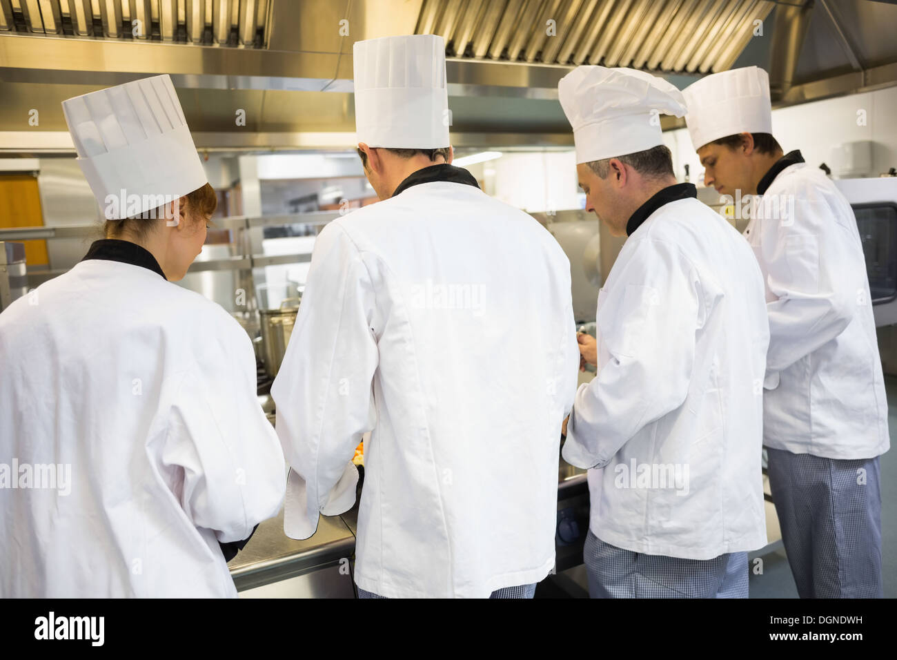 Quattro chef operanti in cucina industriale Foto Stock