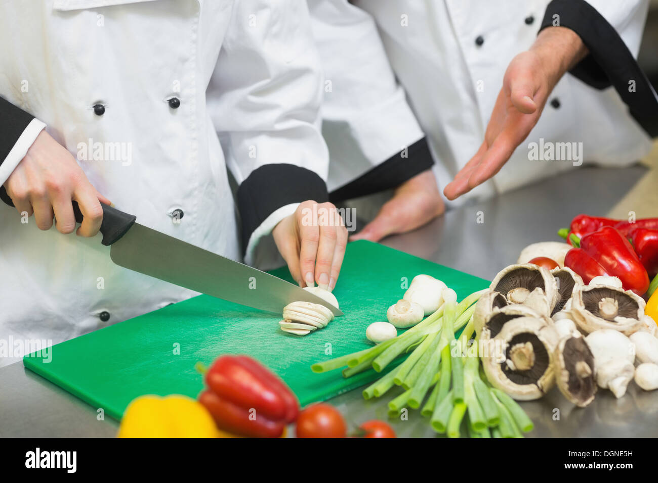 Lo Chef gesticolando presso i suoi colleghi funghi tagliati a fettine Foto Stock