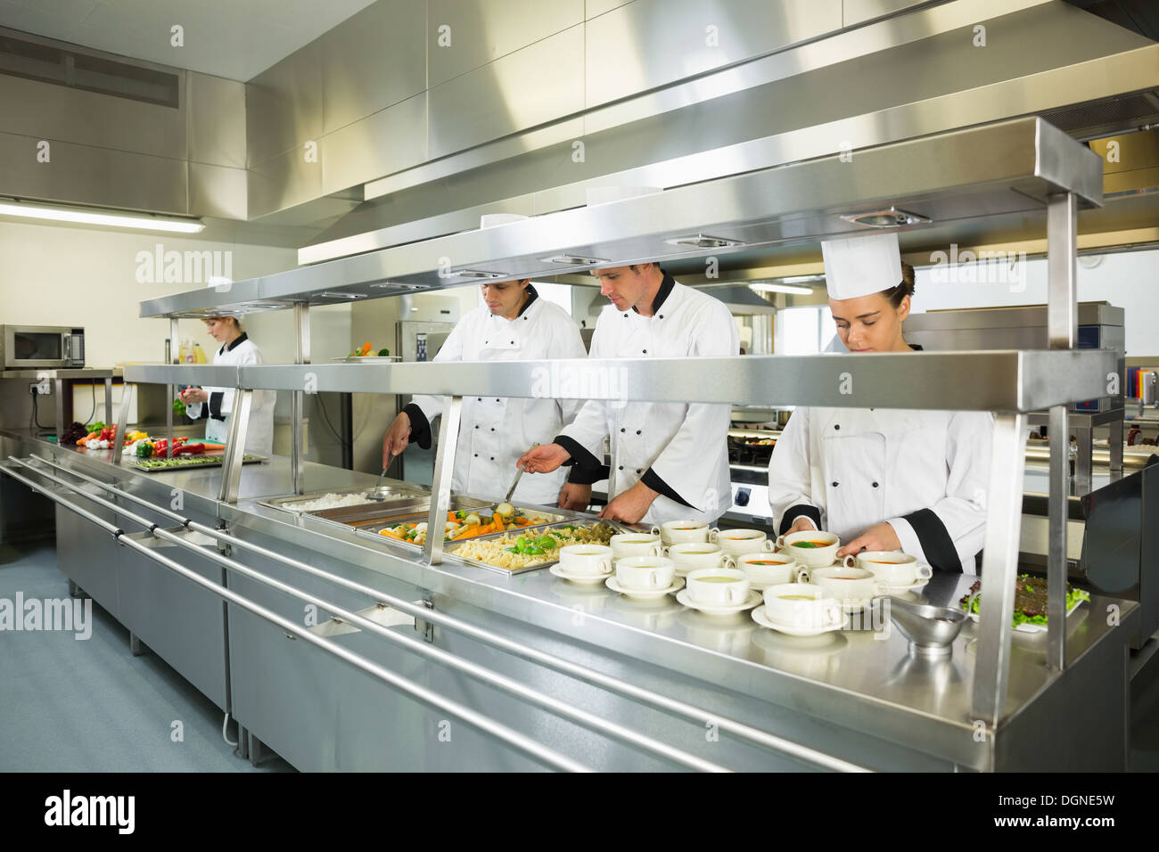 Quattro chef operanti in una grande cucina Foto Stock