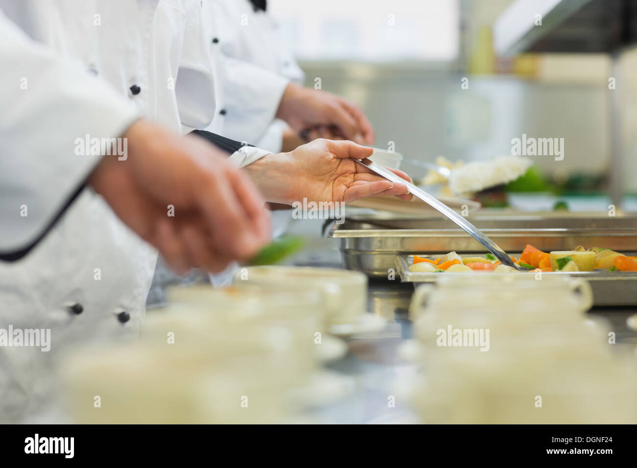 Chef in piedi in una fila nella preparazione degli alimenti Foto Stock