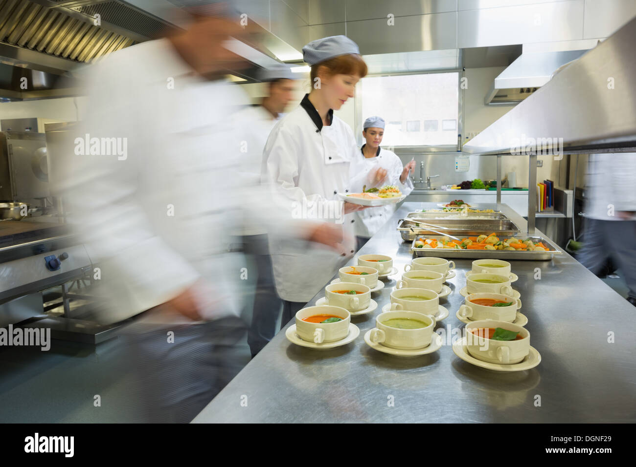 Quattro chef operanti in una moderna cucina Foto Stock