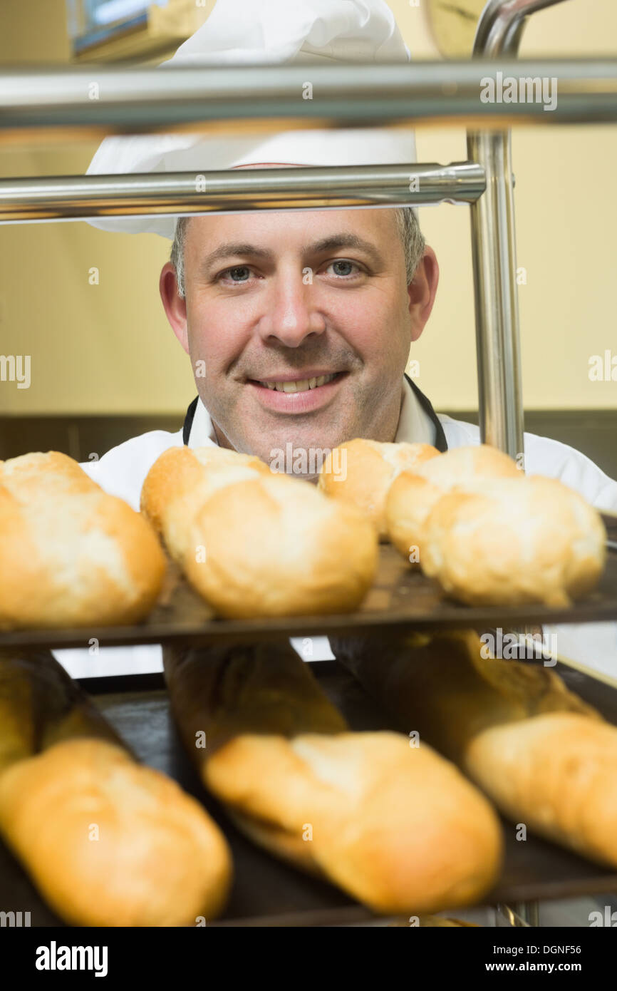 Felice capo chef spingendo un carrello con baguette su di esso Foto Stock