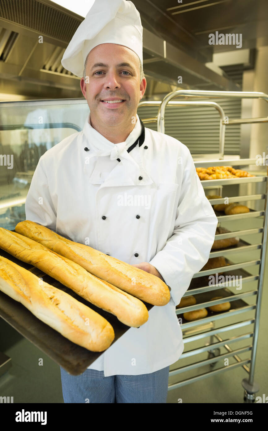 Coppia baker presentando orgogliosamente alcuni baguette su un vassoio da forno Foto Stock